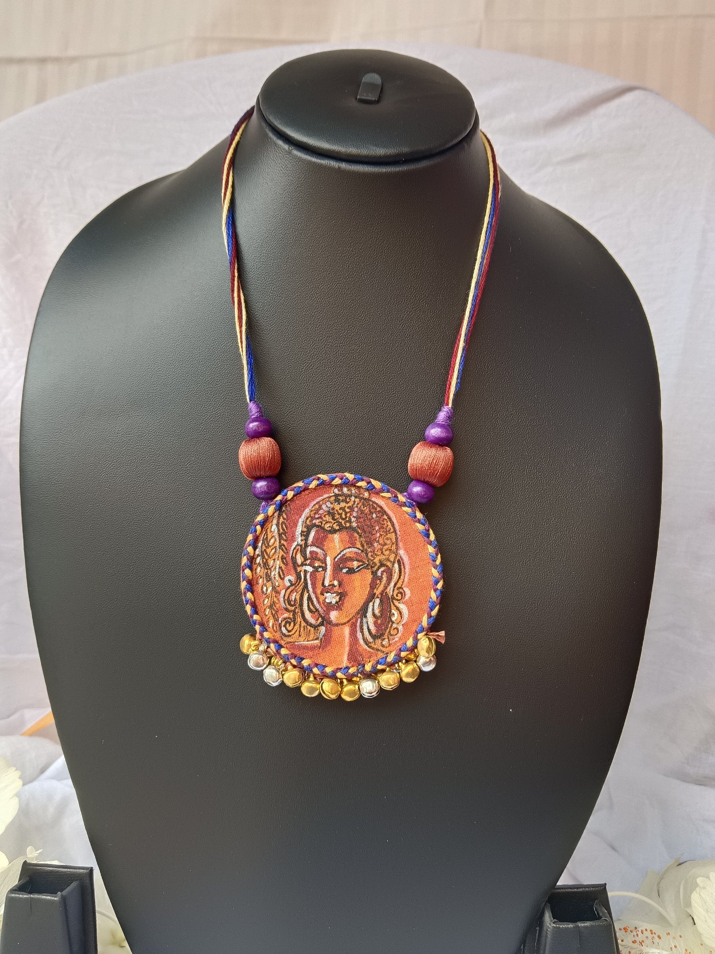 Necklace with a decorative pendant on a black mannequin bust.
